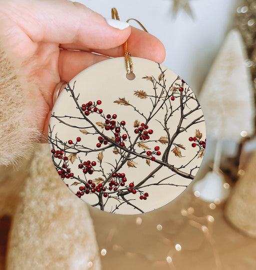 a hand holding a ceramic ornament with berries on it