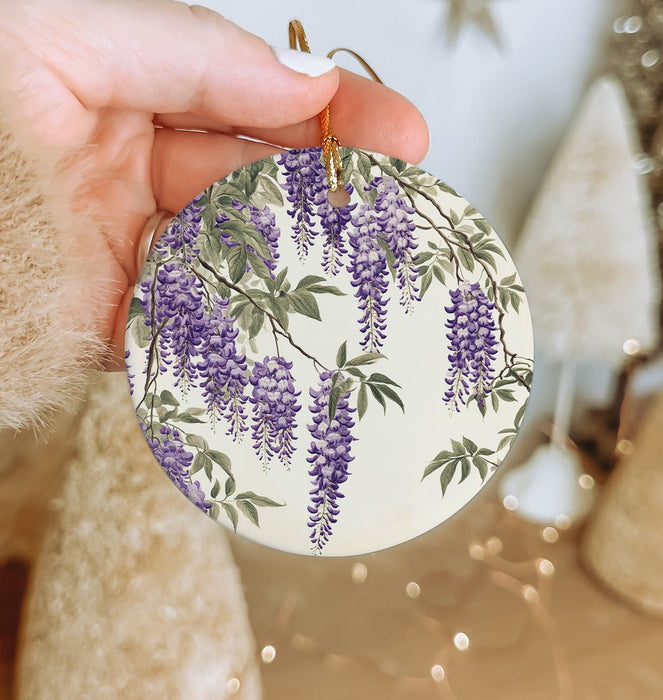 a hand holding a ceramic ornament with purple flowers