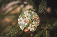 a christmas ornament hanging from a pine tree