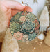 a person holding a round ornament with succulents on it