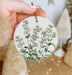 a person holding a round ornament with a plant on it