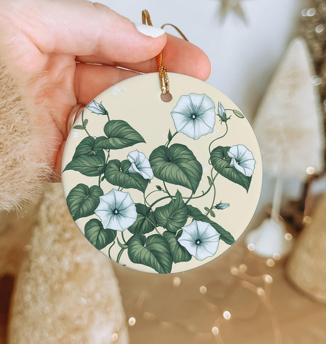 a hand holding a ceramic ornament with flowers on it