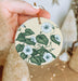 a hand holding a ceramic ornament with flowers on it