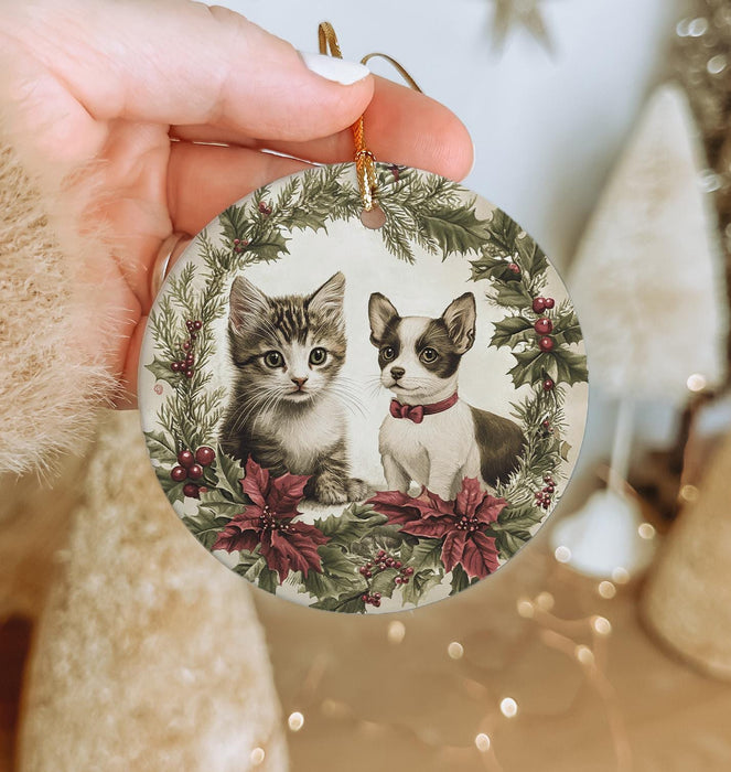 a person holding a christmas ornament with two kittens on it
