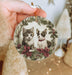 a person holding a christmas ornament with two kittens on it
