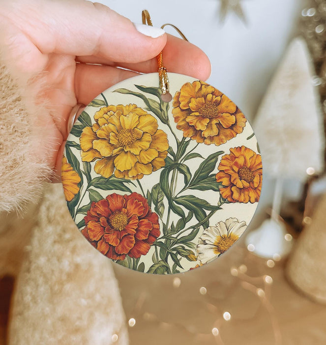 a hand holding a yellow and orange flower ornament