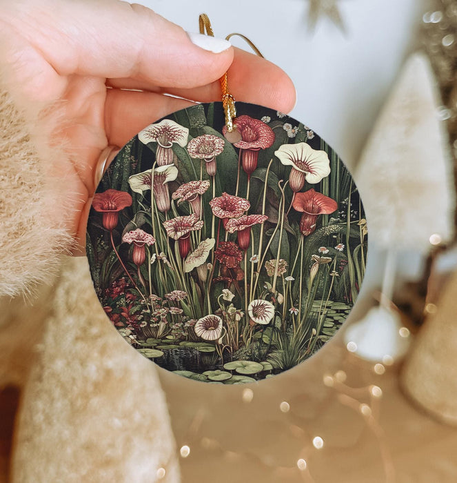 a person holding a christmas ornament with flowers on it