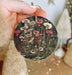 a person holding a christmas ornament with flowers on it