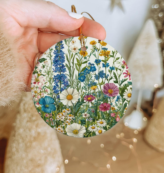 a hand holding a round ornament with flowers on it