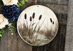 a plate with a picture of a pond and flowers