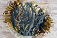 a paper plate with a painting of leaves and flowers on it