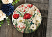 a plate with flowers painted on it next to a bouquet of flowers