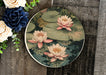 a plate with water lilies on it next to a bouquet of flowers
