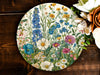 a plate with flowers painted on it next to a bouquet of flowers