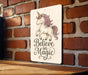 a wooden sign that says believe in magic on a brick wall