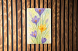 a painting of purple and yellow flowers on a wooden wall