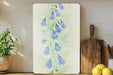 a painting of bluebells on a wall next to a cutting board