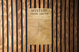 a sign on a wooden wall that says mystery from above