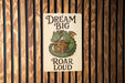 a sign on the side of a building that says, dream big roar loud