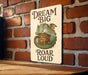 a sign on a brick wall that says dream big roar loud