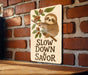 a sign that says slow down and savor on a brick wall