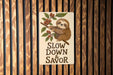 a sticker of a sloth hanging on a wooden wall