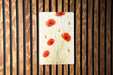 a painting of red flowers on a wooden wall