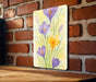 a painting of purple and yellow flowers on a brick wall