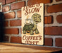 a sign on a brick wall with a turtle holding a cup of coffee