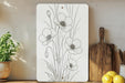 a cutting board with flowers on it next to a potted plant
