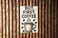 a sign on a wooden wall that says, but first, coffee
