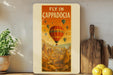 a poster of a hot air balloon flying in cappadocia