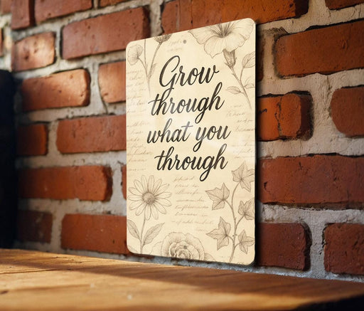 a sign on a brick wall that says grow through what you through