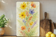 a painting of flowers on a wall next to a cutting board