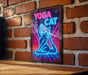 a neon sign that says yoga cat on a brick wall