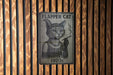 a sign on a wooden wall that says flapper cat