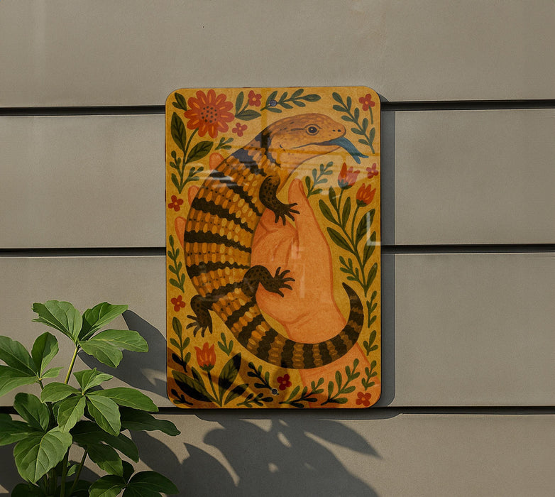 a colorful, hand-painted illustration of a lizard or salamander, surrounded by flowers and leaves, mounted on a wall.