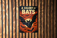 A sign with the text "A COLONY OF BAT" and an illustration of a bat against a dark background with bats flying around it.