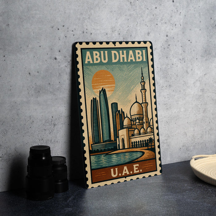 A metal stamp depicting the skyline of Abu Dhabi, with a mosque and skyscrapers, is displayed on a table.