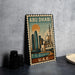 A metal stamp depicting the skyline of Abu Dhabi, with a mosque and skyscrapers, is displayed on a table.
