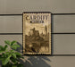 A vintage-style metal sign with the text "CARDIFF WALES" and an illustration of a castle and bridge, mounted on a wall.