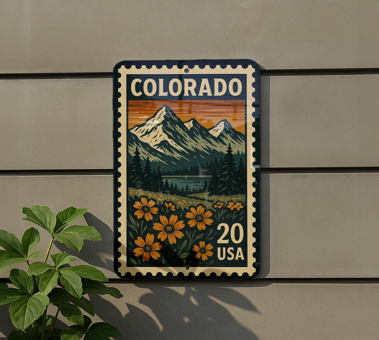A colorful postage stamp depicting a mountain landscape with flowers, mounted on a wall next to a plant.