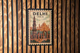A vintage-style poster of the Qutub Minar, a famous monument in Delhi, India, is displayed on a wooden wall.