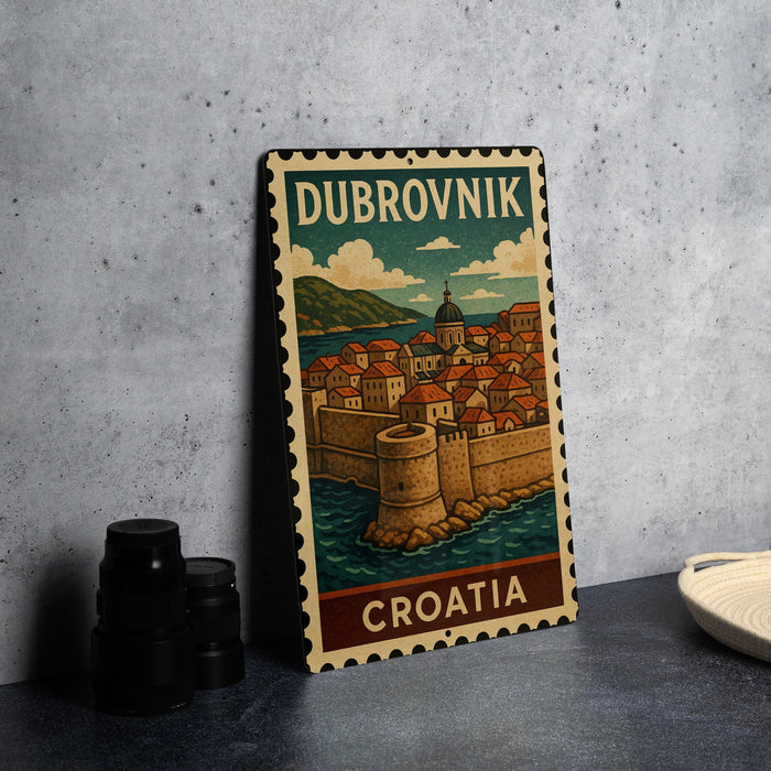 A metal sign with a vintage illustration of Dubrovnik, Croatia, featuring a castle and a coastal town.