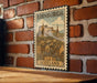 A vintage-style metal stamp depicting the city of Edinburgh, Scotland, with a castle and buildings in the background.