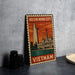 A metal sign with an illustration of Ho Chi Minh City, Vietnam, featuring a tall building and a river, is displayed on a table.
