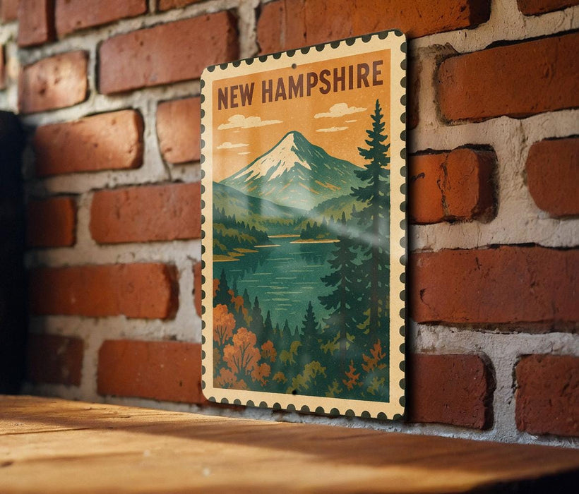 A framed vintage postage stamp depicting a mountain landscape with a lake, hanging on a brick wall.