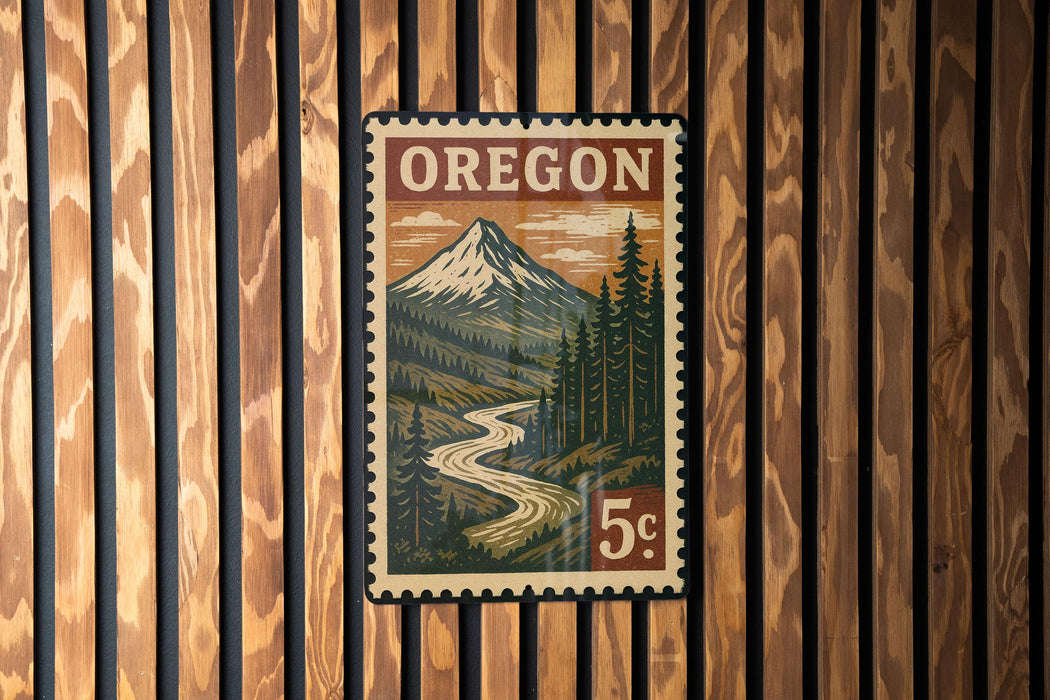 A vintage-style postage stamp from Oregon featuring a mountain landscape with a winding river.