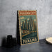 A vintage-style metal sign with the text "PANAMA CITY P" and an illustration of a city skyline, placed on a gray countertop next to some black camera lenses.