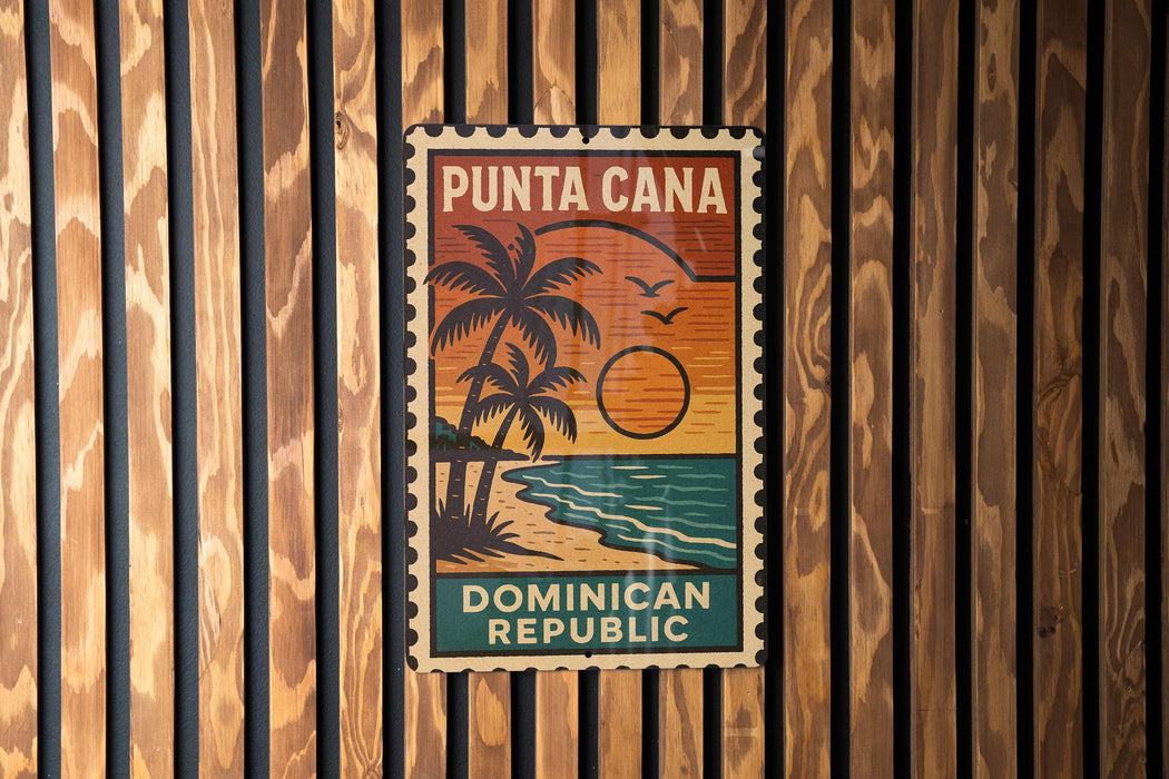 A vintage-style poster of Puna Cana, the Dominican Republic, featuring a palm tree and sunset, is displayed on a wooden wall.